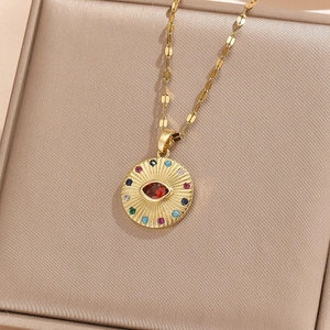 Close-up of golden evil eye coin pendant with colorful zircon stones on jewelry box