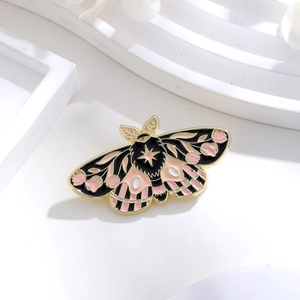Detail shot of moth enamel brooch with floral wing patterns and golden metal trim