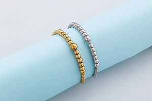 Detail of silver and gold beaded bracelets with large central beads on blue display