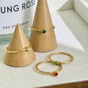Close-up of gold stacking rings with four colored gemstones on wooden cone displays