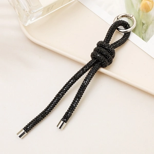 Close-up of black rhinestone chain car keychain with silver metal ring on a tray