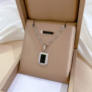 Détail d'un collier chaîne torsadée argentée avec pendentif rectangle noir en coffret