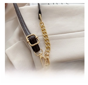 Detail of adjustable brown leather strap with gold buckle and textured pattern