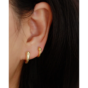 Minimalist gold huggie hoop earrings with smooth teardrop and beaded designs on ear