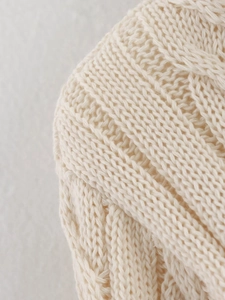 Close-up detail of off-white chunky knit fabric with textured cable stitch patterns