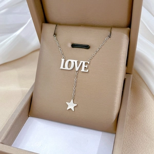 Close-up of silver LOVE necklace with star pendant inside a brown jewelry gift box