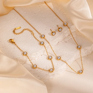 Detail of gold jewelry set with grey beads on white stone and beige silk background