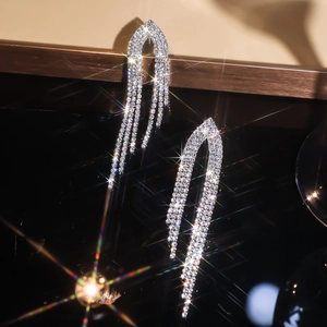 Close-up of sparkling silver rhinestone tassel earrings on a sleek black background