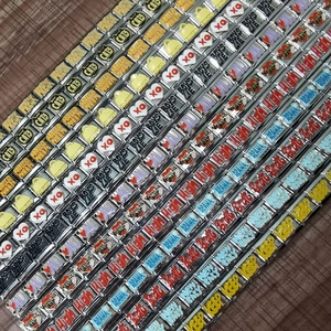 Macro shot of assorted gold metal modular beads with engraved patterns and slogans on wood