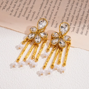 Detail of gold flower earrings featuring crystal studs and long white pearl tassels
