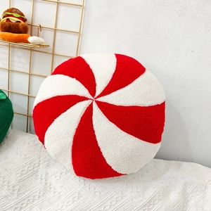 Peppermint style plush round pillow with red and white spiral stripes on white knit blanket