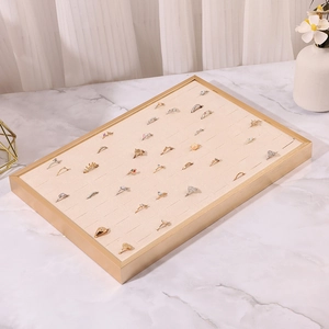 Detailed view of beige jewelry display tray with gold frame on marble surface