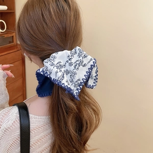 Detail of blue floral knot headband showing the textured fabric and wavy stitched edge
