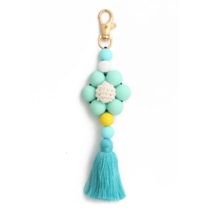 Close-up of mint green silicone flower keychain with a crochet center and matching tassel