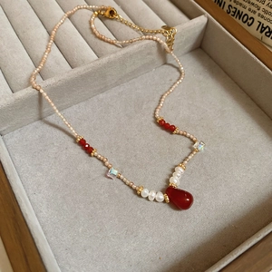 Detail view of 18k gold plated necklace with pink beads and red water drop pendant