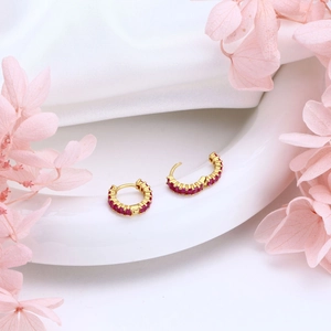 Detailed close-up of gold S925 silver hoop earrings with inset red zircon gemstones