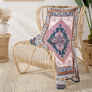 Detail view of a Persian patterned flannel blanket draped over a rattan chair in a cozy room