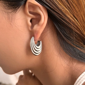 Minimalist silver hollow oval earrings with layered arc design worn on the ear model