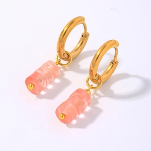 Détails de pendentifs en bambou rose sur des créoles minimalistes en métal doré