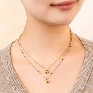Détail d'un collier double épaisseur à cœur doré avec perles colorées sur modèle
