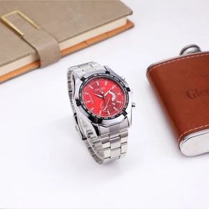 Close-up of chronograph watch with red dial, tachymeter bezel, and steel strap detail