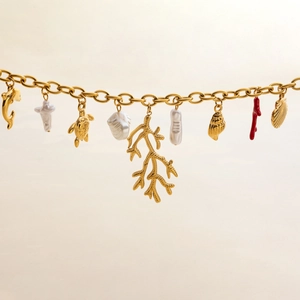 Detailed view of gold ocean charms including dolphin, turtle, shell and coral on chain