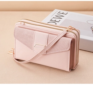 Detail view of pink leather crossbody phone bag with double zippers and gold metal trim