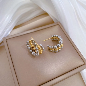 Detail of two-tone gold and silver beaded C-shape titanium steel hoop earrings on stand