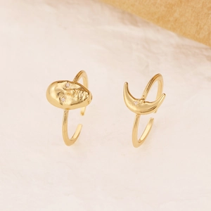 Detail of gold-plated adjustable rings with artistic face and crescent moon designs