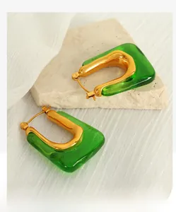 Detail of emerald green resin U-shaped earrings with matte gold titanium steel accents