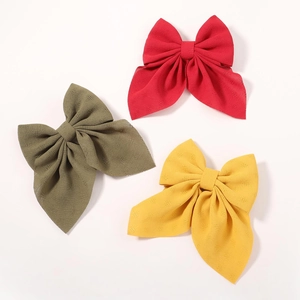 Close-up of three layered floral chiffon bow hair clips in red, olive and yellow