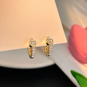 Détail macro de boucles d'oreilles cœur dorées avec sertissage pavé de zircons blancs