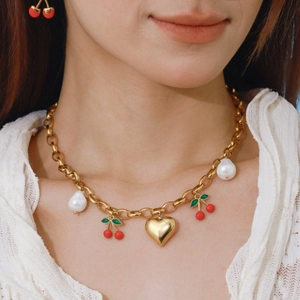 Collier à grosse chaîne dorée avec pendentifs cerise, cœur et perles blanches