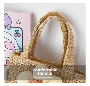 Detail of woven straw handbag featuring soft cream floral ornament and thick handles