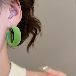 Gros plan d'un mannequin portant des créoles vertes floquées au fini velours mat