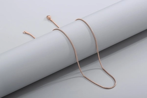 Detailed view of a sleek rose gold snake chain necklace on a minimalist display stand