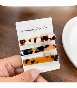 Three acetate hair clips in amber and tortoiseshell patterns on a white display card