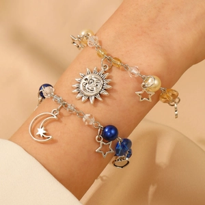 Detail of celestial bracelets featuring sun and moon pendants with blue and pearl beads