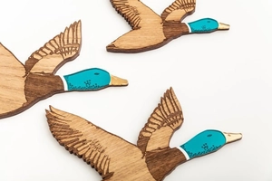 Détail de trois canards muraux en bois avec têtes en acrylique vert et accents dorés fins