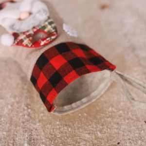 Detail of burlap Christmas stocking with red and black plaid trim and hanging loop
