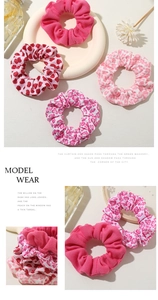 Close-up of four pink hair scrunchies with heart patterns and floral fabric textures
