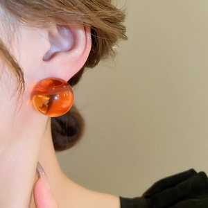 Gros plan d'un mannequin portant une boucle d'oreille boule en résine ambrée translucide