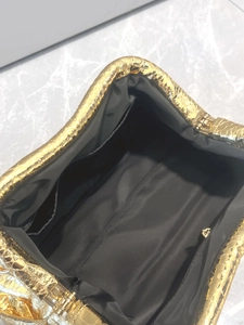 Detailed view of gold snakeskin clutch interior with black fabric lining and zip pocket