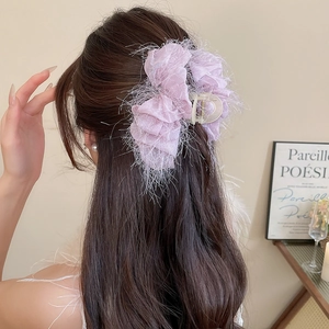 Détail d'une grande pince à cheveux violette à franges sur cheveux ondulés foncés
