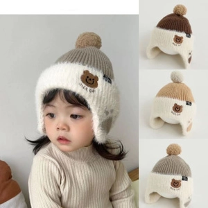 Dettaglio del cappello invernale in maglia con pompon e ricamo di orsetto