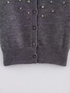 Detail of dark gray knit cardigan with rhinestones and brown buttons for women