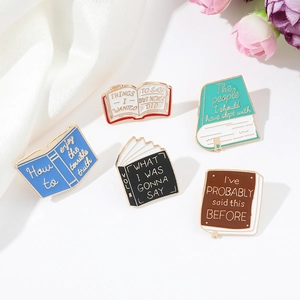 Macro shot of five vintage metal book enamel pins on white silk with elegant floral accents