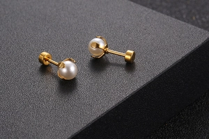Macro shot of gold titanium stud earrings with crown-set white pearls and screw back