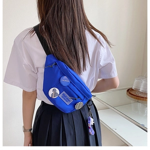 Detailed back view of a blue nylon chest bag with colorful patches and purple charm