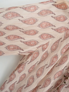 Macro detail of beige paisley chiffon fabric with elegant gold lurex metallic stripes
